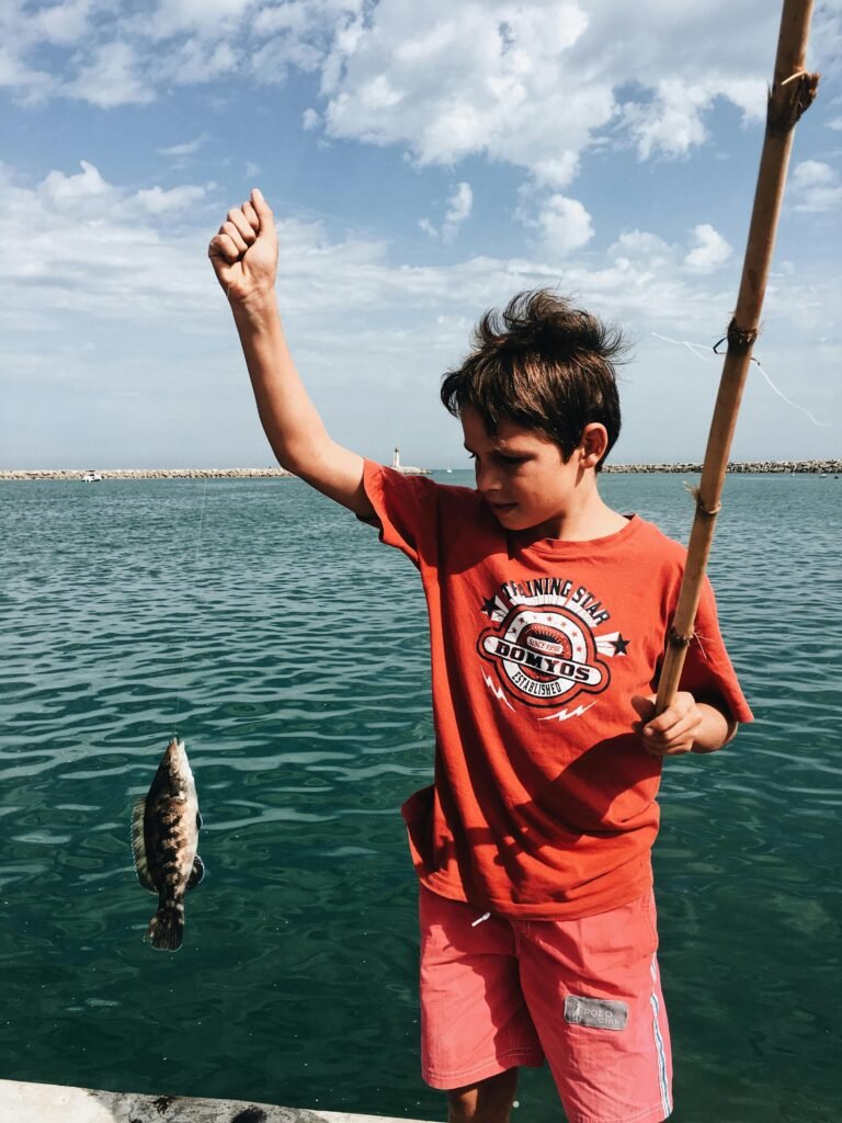 pexels-photo-3099187-3099187-1 Young boy celebrates catching a fish on a sunny day by the sea.